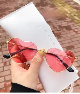Detail of red heart-shaped sunglasses with gold metal frame and spring hinges