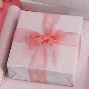 Pink heart pattern gift wrapping paper with sheer chiffon ribbon bow on white gift box