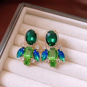 Macro shot of green crystal flower earrings with rhinestones in a velvet jewelry box