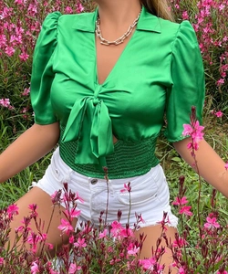 Detail of green satin short sleeve top featuring a V-neck and front bow tie closure