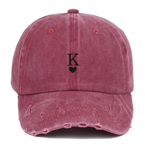 Close-up of vintage washed red baseball cap with embroidered heart K and distressed brim