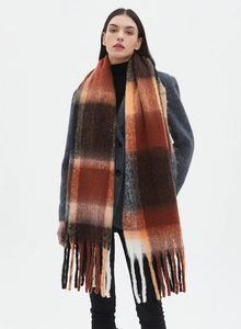 Close-up of orange and brown plaid scarf with soft fringe tassels and oversized knit texture