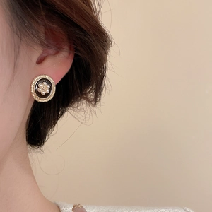 Detailed close-up of a vintage-style round gold earring with pearls worn by a model