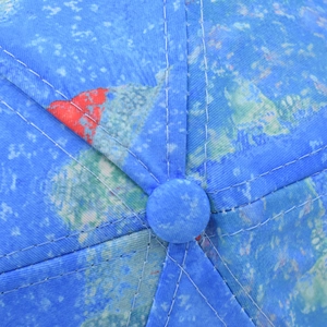 Macro detail of cotton baseball cap top showing blue map print and durable stitching