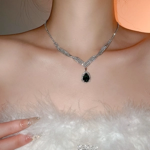 Detail shot of a pear-cut dark green gemstone pendant on a silver chain necklace