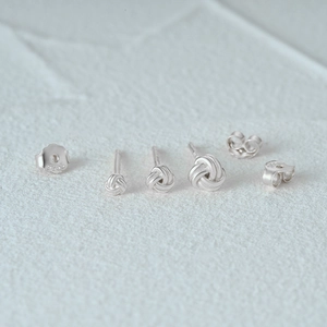 Detailed macro view of S925 sterling silver woven knot stud earrings on white stone