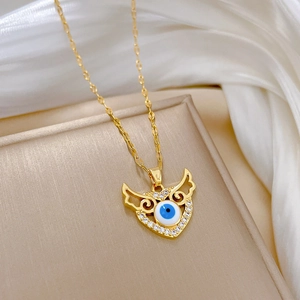 Macro view of gold-plated heart wings necklace with blue evil eye and white zircon inlay