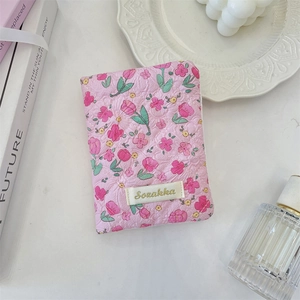 Detail of pink tulip floral quilted fabric and woven brand label on a travel pouch