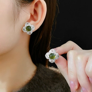 Detail view of silver clover stud earrings with green stones and sparkling zircon pavé