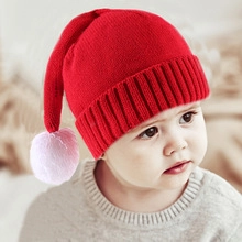 Close-up of a red cable-knit baby beanie featuring a large soft pink faux fur pompom on top