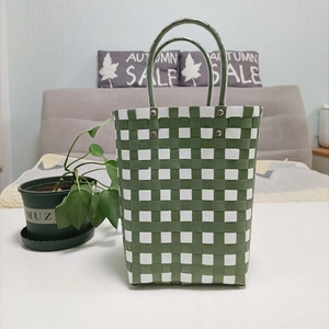 Detail of green and white checkered woven bucket bag showing its texture and sturdy handle