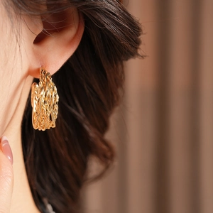 Close-up of 18K gold plated twisted C-shaped earrings on model for a minimalist style