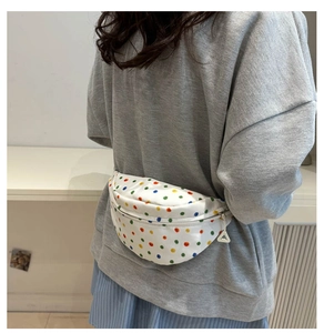 Rear view of a model wearing a white canvas waist bag with colorful polka dots over a hoodie