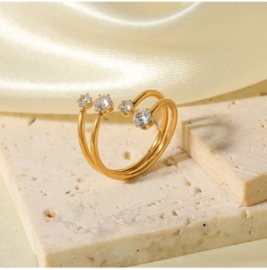 Gros plan sur la bague ouverte dorée à double couche sertie de quatre zircons brillants