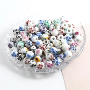 Round ceramic beads with colorful floral patterns in a glass bowl for DIY jewelry