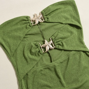 Detail of green backless dress featuring two gold starfish metal buckles on the chest