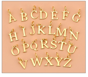 Macro view of 26 gold-plated letter pendants from A to Z on a soft pink background