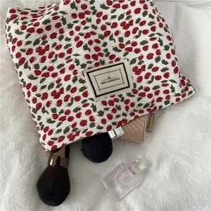 Detailed macro view of pleated fabric floral makeup bag with Pleasant Time woven label