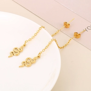French vintage style golden snake pendant earrings with long chain on a white plate