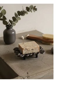 Detail of vintage cast iron soap dish with floral pattern and natural bar soap on stone