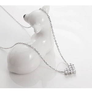 Close-up of silver heart pendant with sparkling crystals on a decorative white stand