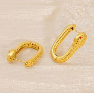 Gros plan de boucles d'oreilles serpent dorées avec yeux rouges et texture écailles