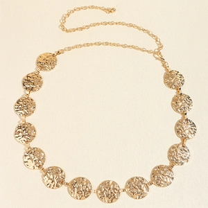 Close-up of golden metal chain belt featuring hammered circular textured discs and links