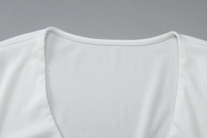 Détail de l'élégant décolleté en V et de la texture en maille côtelée sur le haut blanc