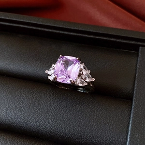 Macro shot of silver ring with cushion-cut purple gemstone and pear-cut diamonds in leather box