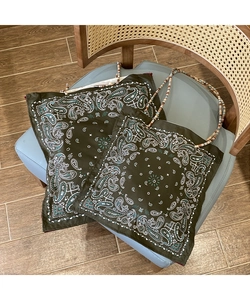 Detail view of paisley print tote bag featuring unique beaded handles on a casual chair