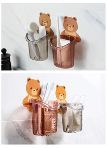Detail of wall-mounted bear cup holders in brown and grey for bathroom storage