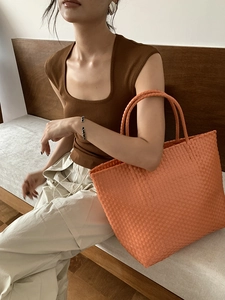 Detail of an orange woven straw tote bag with a high-capacity design for summer vacations