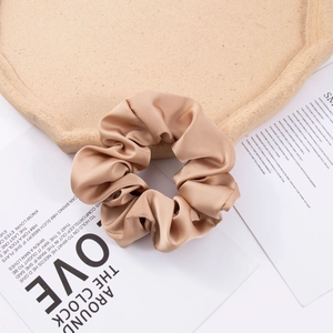 Detail of a large champagne silk satin scrunchie with soft folds and elegant glossy texture