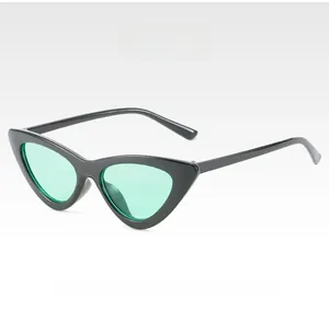 Detail of black cat-eye sunglasses featuring transparent green lenses and glossy frames