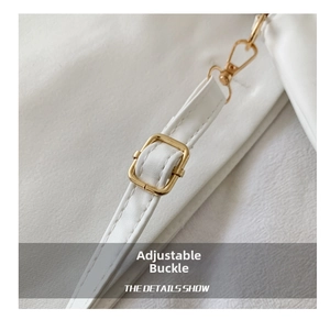 Detail view of the white shoulder strap with an adjustable gold metal buckle on the bag