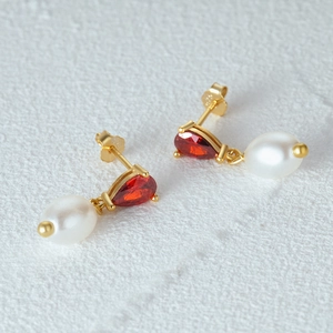 Detailed macro shot of S925 silver earrings with red teardrop gems and white pearls