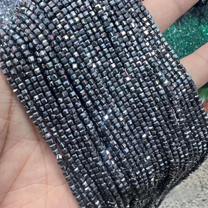 Macro shot of faceted terahertz energy beads showing dark grey metallic luster and cube cut