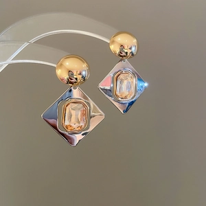 Détail macro de boucles d'oreilles géométriques bicolores avec cristal ambré sur présentoir