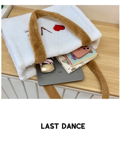Plush white tote bag with red heart embroidery showing iPad and books inside on wooden table