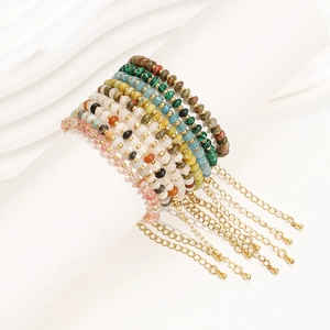 Détail de bracelets bohèmes en pierres naturelles avec breloques dorées sur support blanc