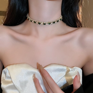 Gros plan d'un choker doré avec pendentif en pierre verte sur un mannequin