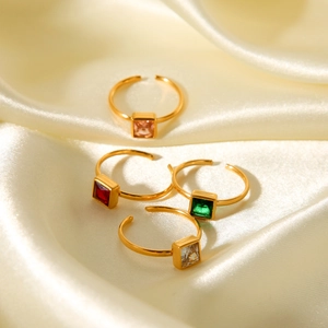 Detail of four gold-plated stainless steel rings with square zirconia in multi-colors