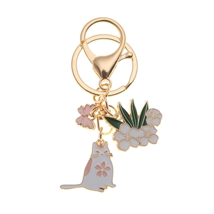 Golden metal keychain with pink cherry blossom cat and flower charms on white background