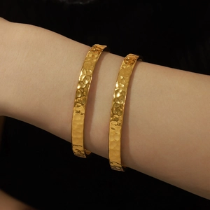 Elegante bracciale aperto placcato oro con texture martellata in acciaio titanio