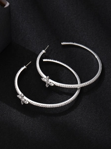 Macro shot of silver cross hoop earrings with sparkling cubic zirconia on black silk