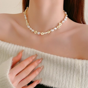 Detail view of pearl and white flower bead necklace with gold spacers on model
