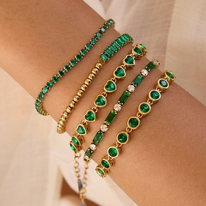 Close-up of five layered 18K gold-plated bracelets featuring green zircon gemstones on wrist