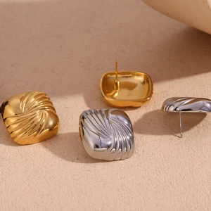 Macro detail of square 18K gold and silver earrings with radial spiral texture