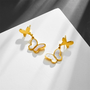 Macro shot of elegant butterfly tassel earrings in gold metal and white shell finish