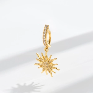 Macro shot of gold sun pendant navel ring with sparkling cubic zirconia on white background